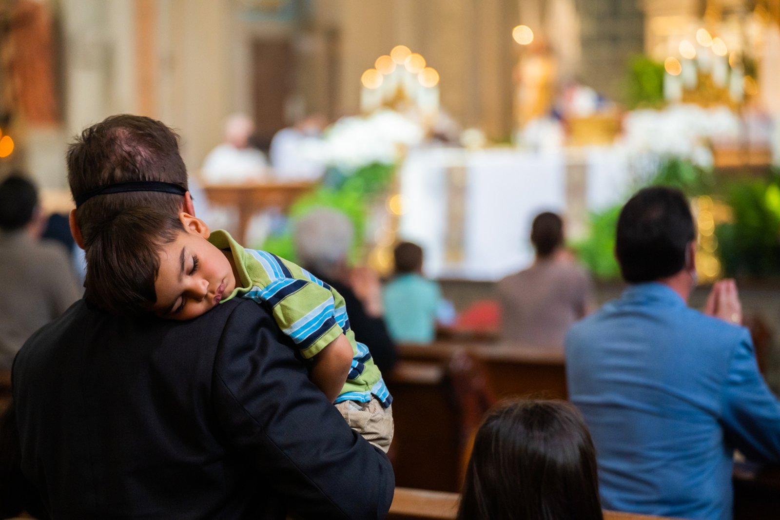 A child sleeps on his father's shoulder during a Mass and May crowning at Old St. Mary's Parish in 2021. (Valaurian Waller | Detroit Catholic)