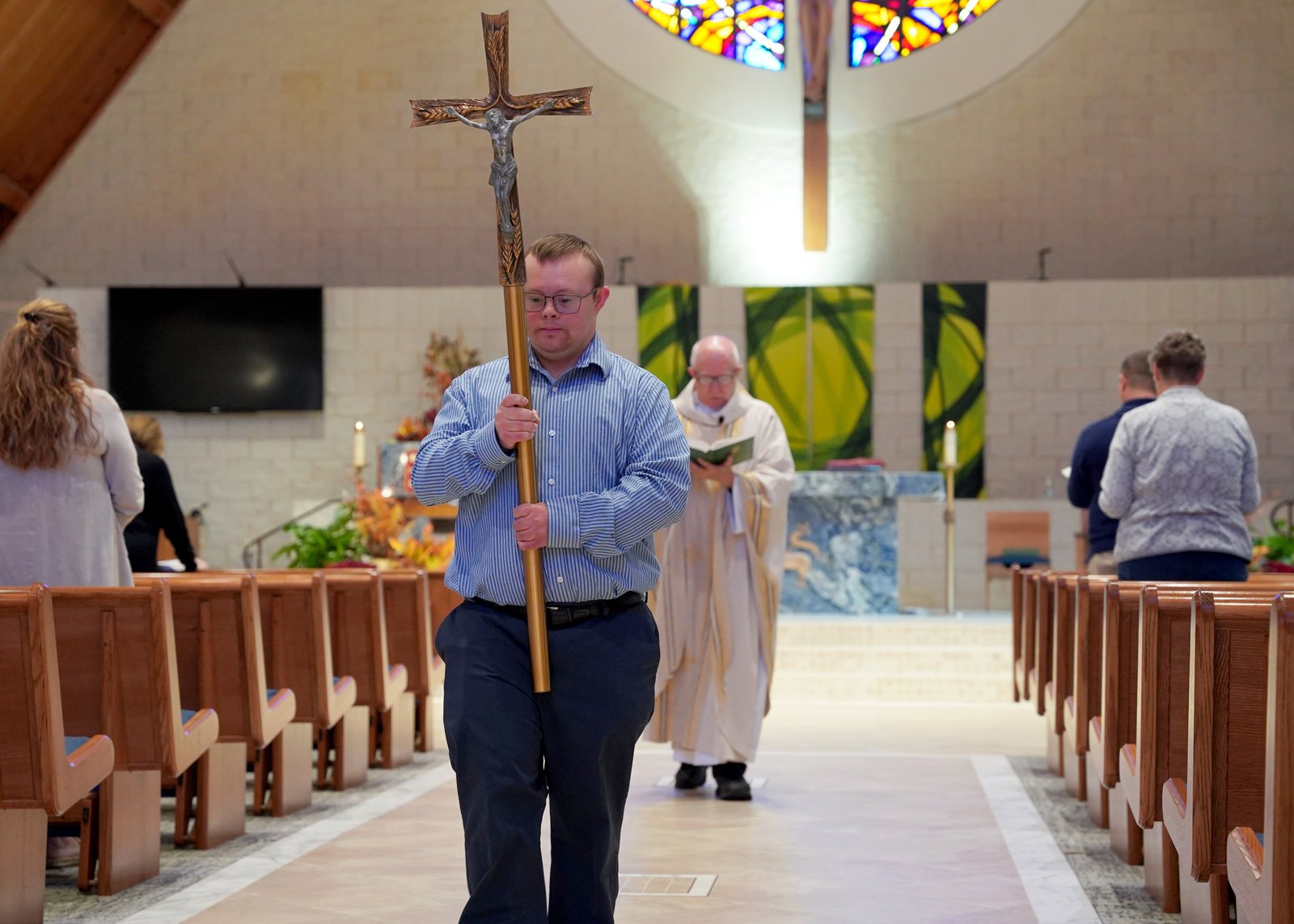 Robby Heil carries the cross in procession during weekday Mass at St. James Parish in Novi, as Fr. Ed Zaorski celebrates.