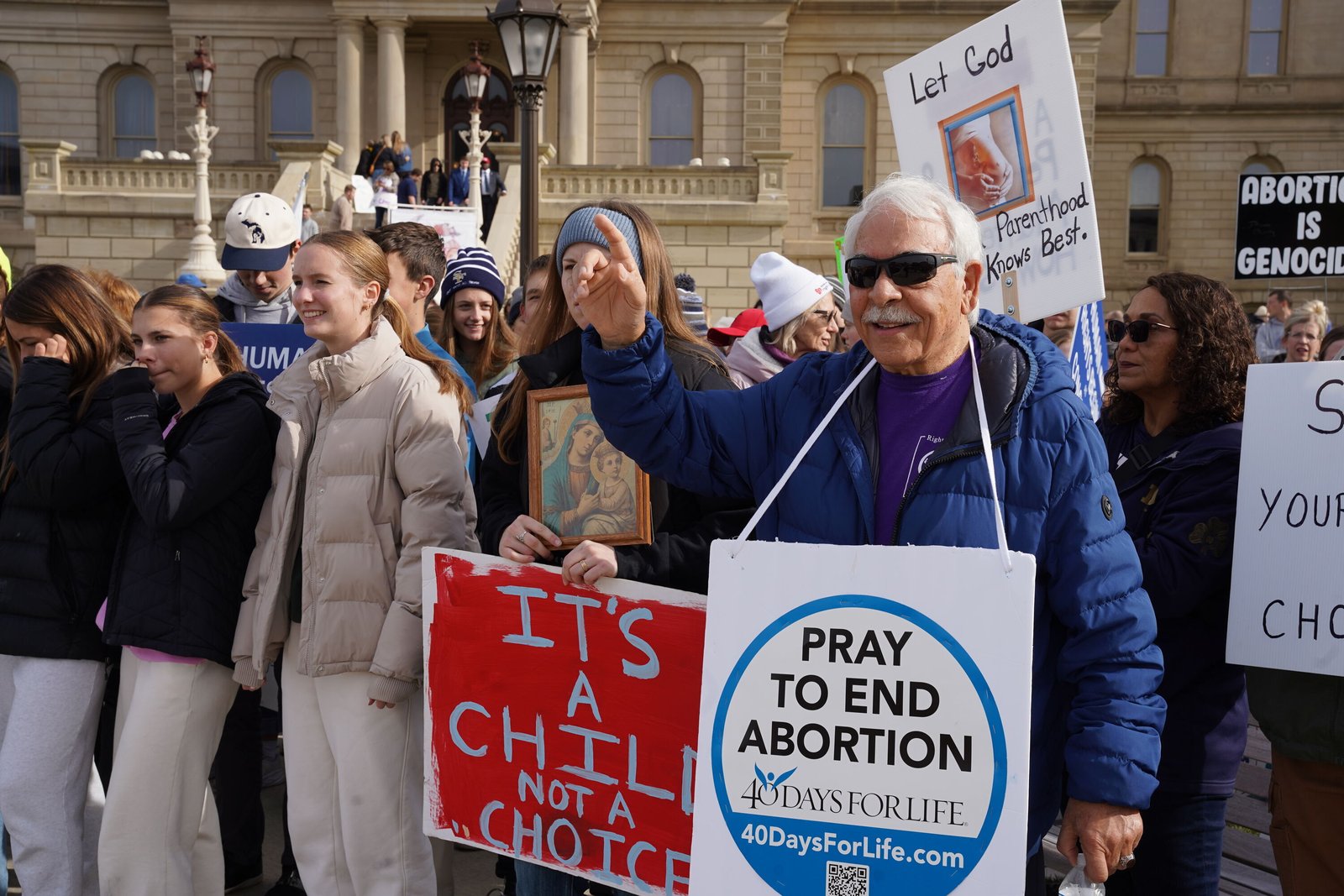 Marchers hold signs and banners on the Capitol lawn during the Michigan March for Life, which drew thousands from across Michigan on the anniversary of the 2022 passage of Michigan's Proposal 3.