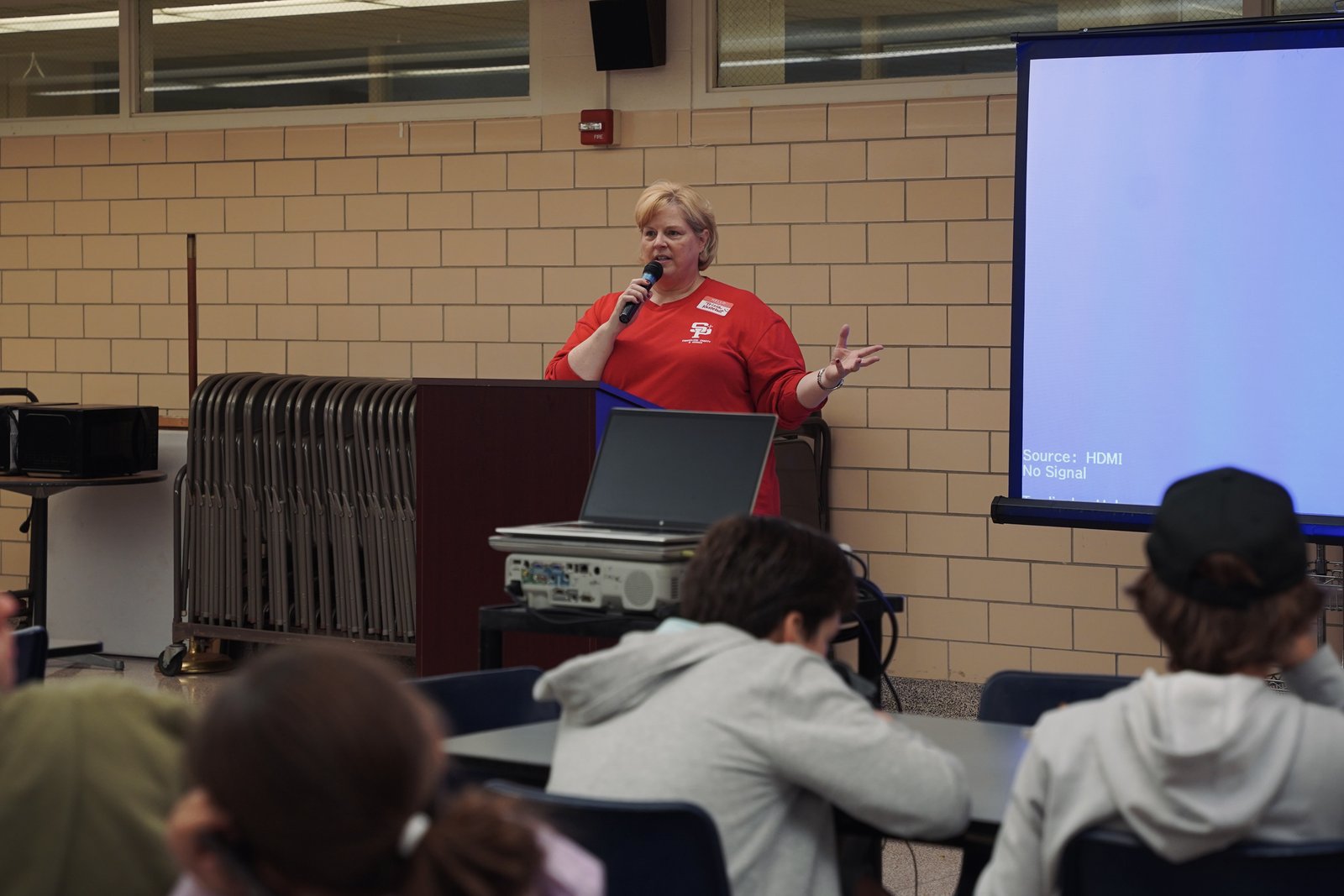 Tricia Kesteloot, director of evangelical charity at St. Paul on the Lake Parish, offers remarks during the meal-packing event Oct. 18.