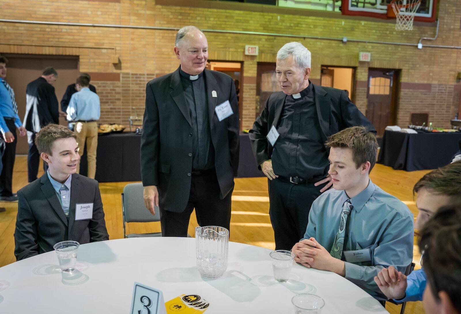 Mons. Trapp (segundo a la derecha) y el P. Tony Richter conversan con jóvenes en una cena de discernimiento vocacional con el Arzobispo de Detroit, Allen H. Vigneron, en el Sacred Heart Major Seminary el 28 de marzo de 2023. Mons. Trapp fue director espiritual de seminaristas y profesor asociado de teología, liturgia y sacramentos en el seminario por más de 35 años. (Valaurian Waller | Detroit Catholic)