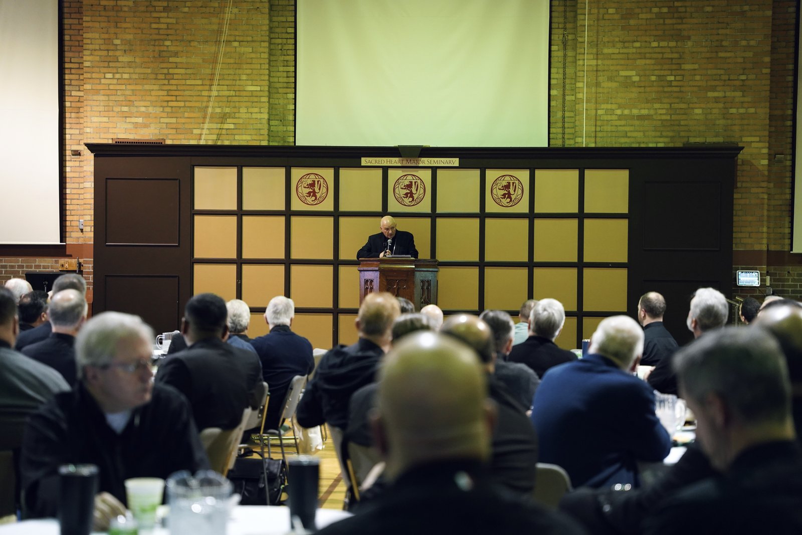 Archbishop Weisenburger offers words of encouragement as nearly 175 priests gather in Sacred Heart's gymnasium to begin their three-day working session. (Izzy Cortese | Detroit Catholic)