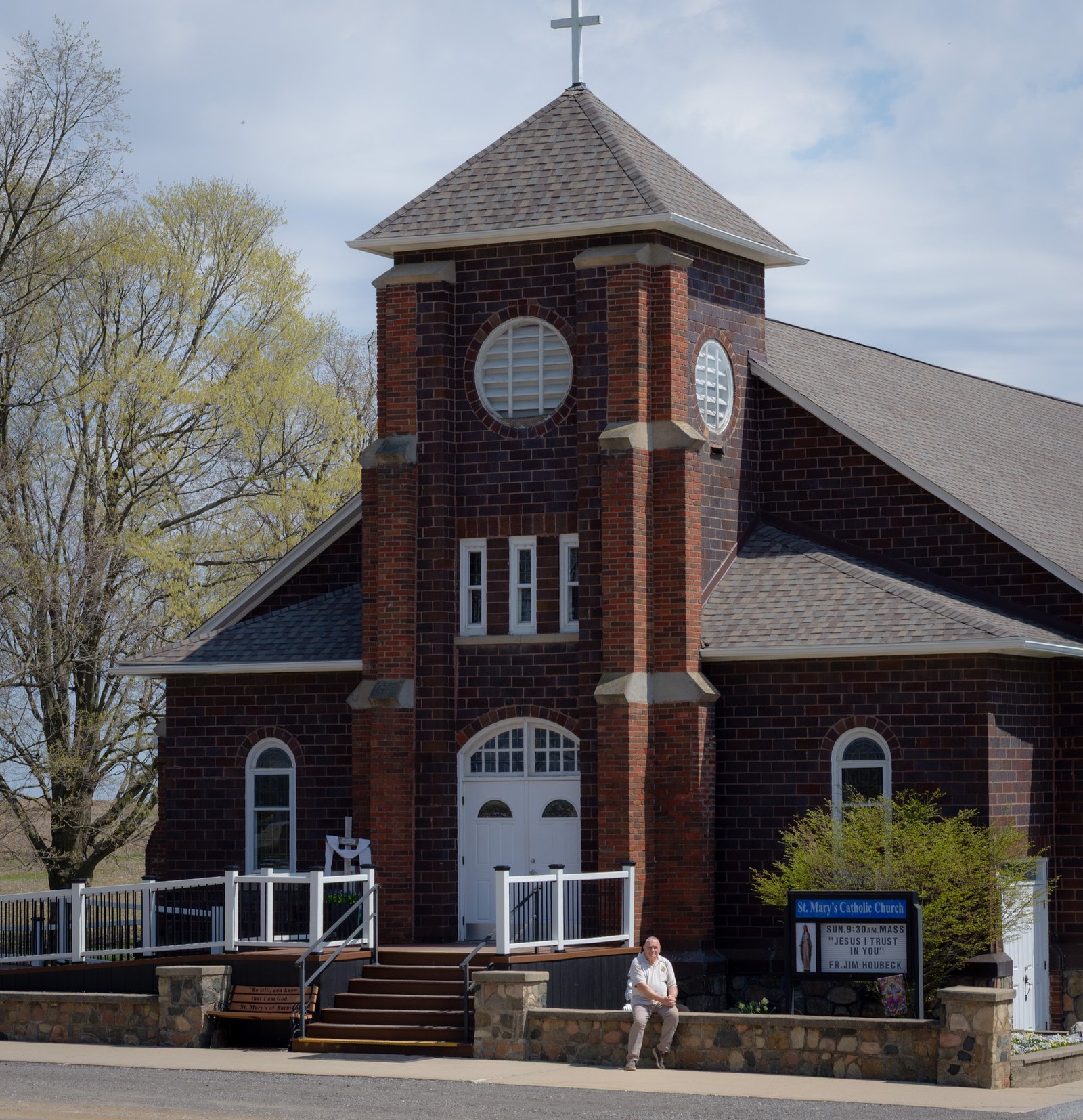 Wilson Almand sits near the front steps of St. Mary Burnside Parish in North Branch, which is believed to be the only parish in the Archdiocese of Detroit on a dirt road. (Courtesy of Kimberly Kelsch)