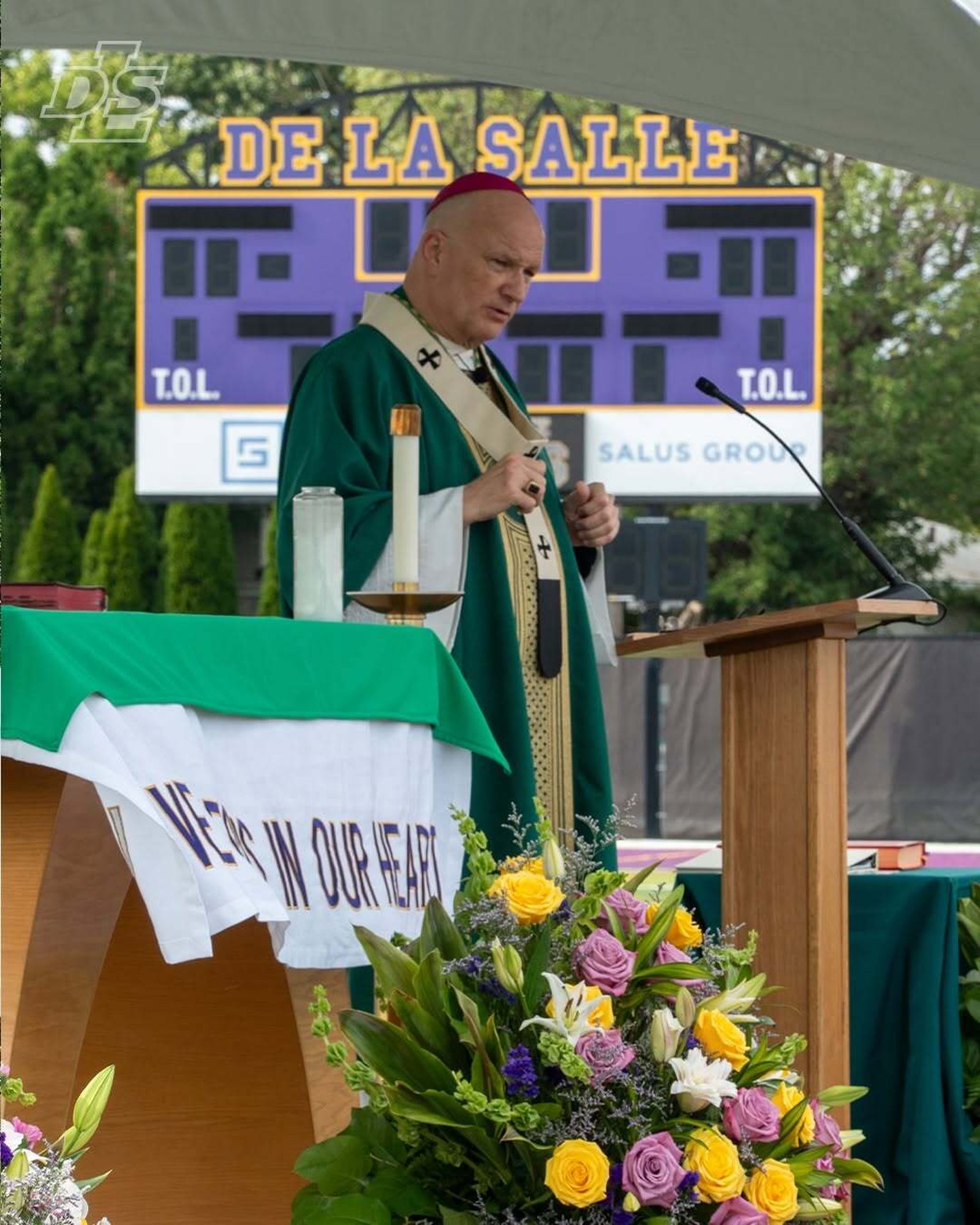 Archbishop Weisenburger gives a homily during the centennial Mass on the school's football field.