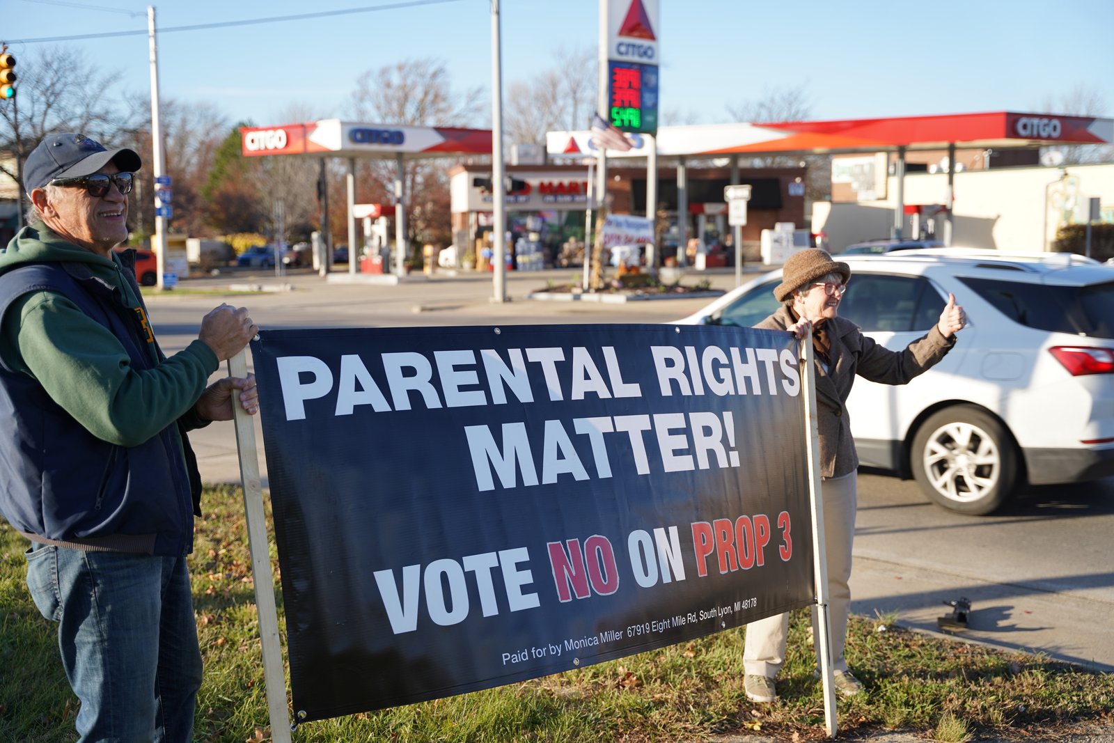 Debbie Bloomfield y Emmanuel Laghermo de la parroquia Our Lady of the Scapular en Wyandotte sostienen un cartel que informa a los votantes sobre las consecuencias de la Propuesta 3 en la intersección de las calles Allen y Southfield en Allen Park el 7 de noviembre. Bloomfield dijo que los voluntarios continuaron yendo de puerta en puerta el día de las elecciones, el 8 de noviembre, para animar a los votantes que aún podrían estar indecisos a votar "no".