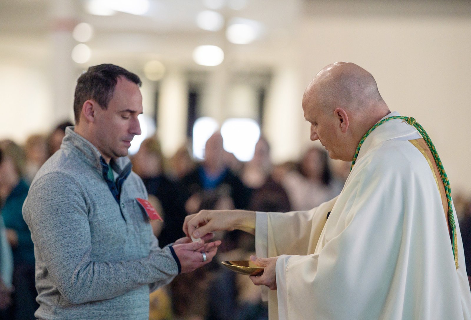 Archbishop Weisenburger offers Communion during Mass at the Suburban Collection Showplace in Novi. In his homily, the archbishop recalled the impact of his second-grade teacher, encouraging educators to remember the influence they'll have on young hearts and minds.