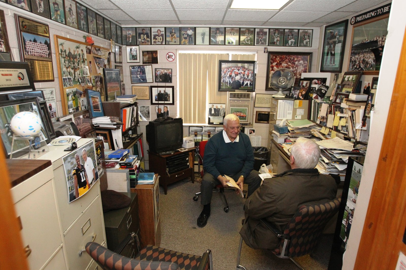 Legendary Brother Rice football coach Al Fracassa sits down with Michigan Catholic reporter Don Horkey in his office in January 2014, every square inch of which was covered with memorabilia from his 54-year coaching career. (Detroit Catholic file photo)