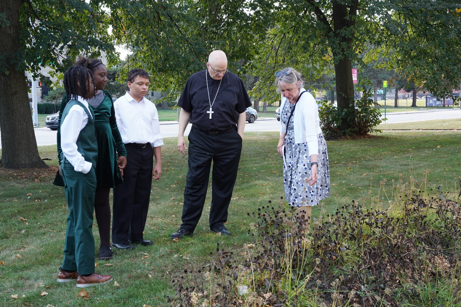 Archbishop Weisenburger examines the bioswales in the school’s front law that are built to handle 2,891 cubic feet of water. The bioswales feature native plants to the region.