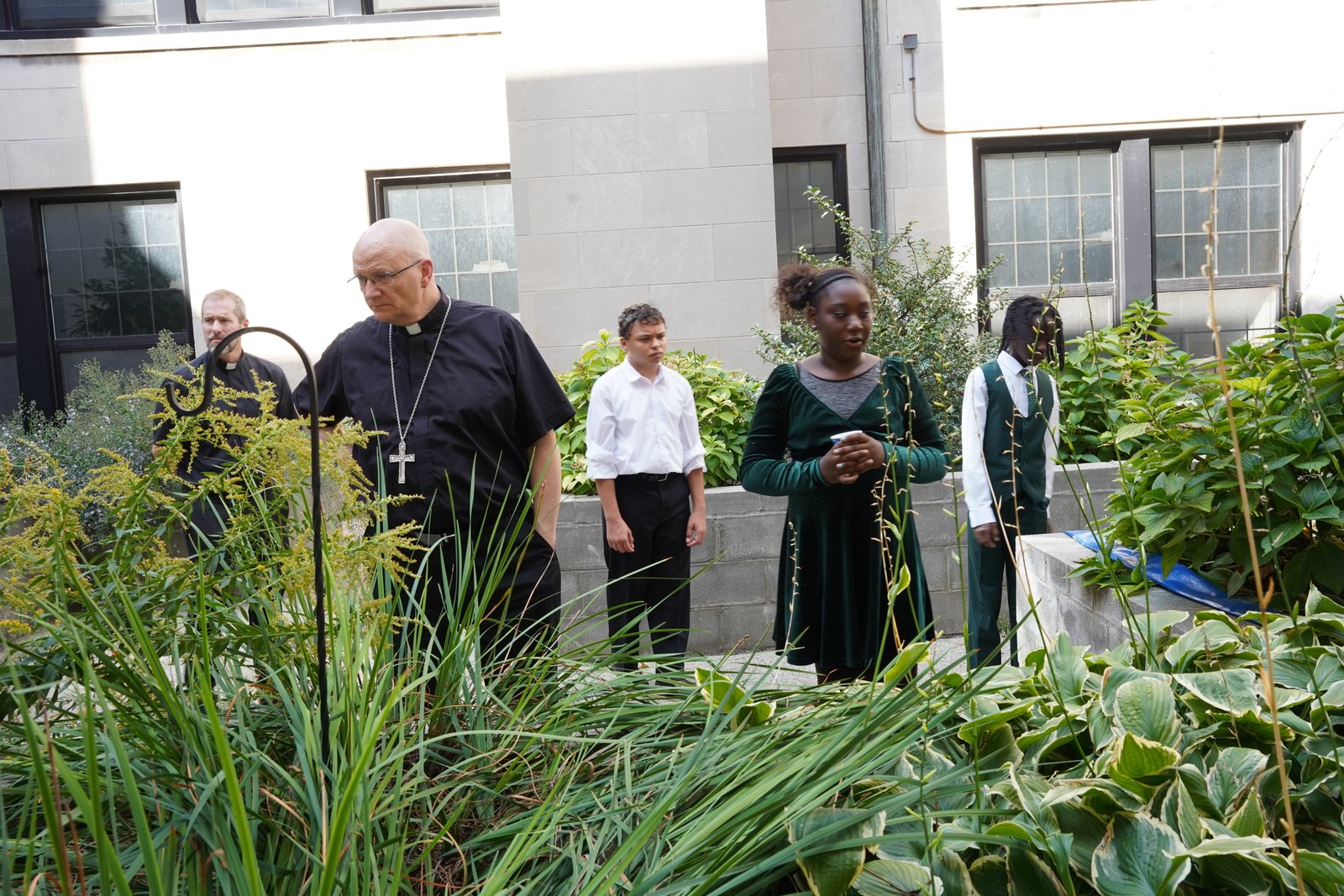 Gesu students show Archbishop Weisenburger the rain gardens in the school's courtyard, which help divert rainwater away from the stormwater system. The courtyard features five 500-gallon rain barrels.