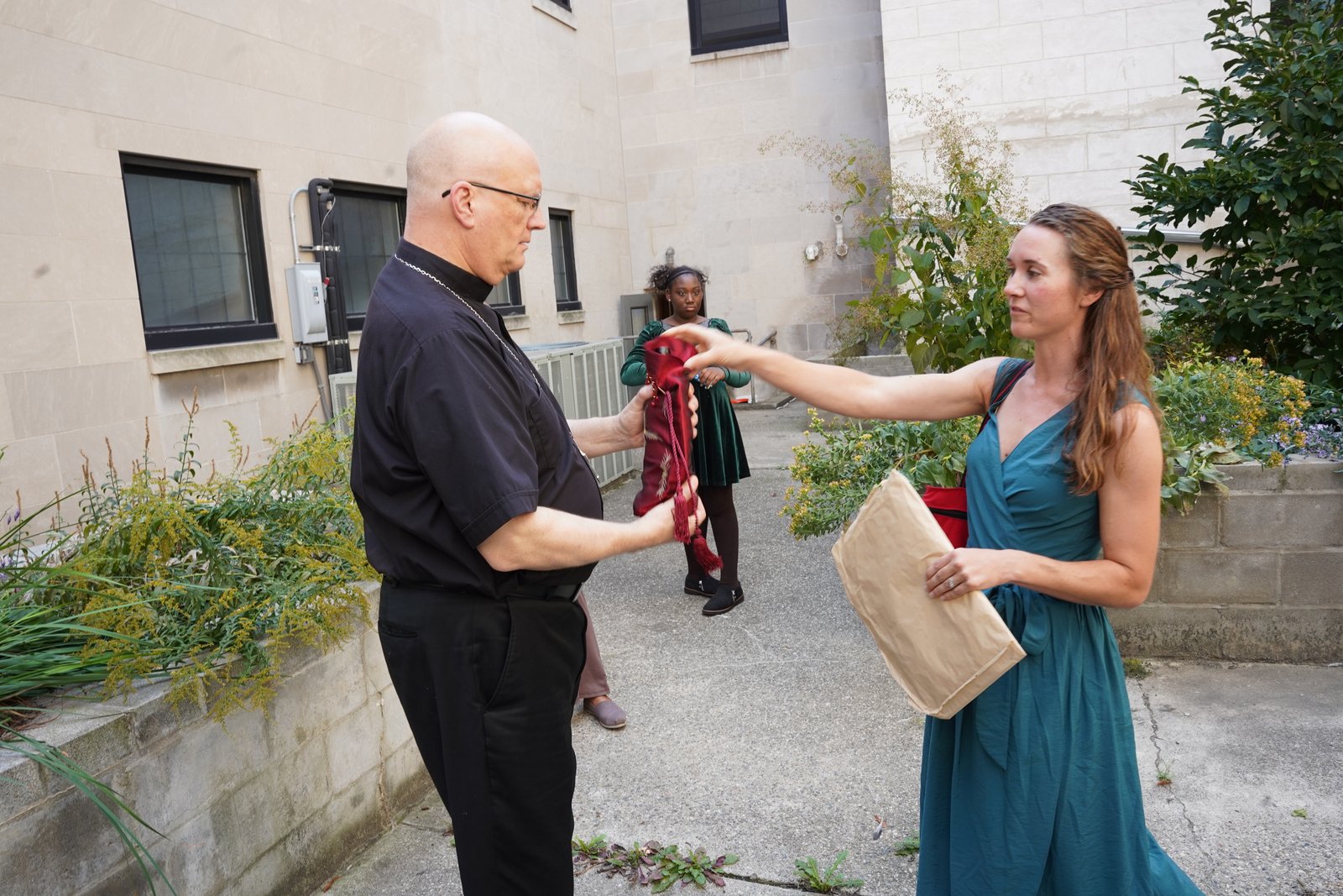 Stephanie Osborn of the Gesu Parish Green Team gifts Archbishop Weisenburger with a bottle of wine from the parish's own vineyard. Some of the wine was used for celebrating Mass.