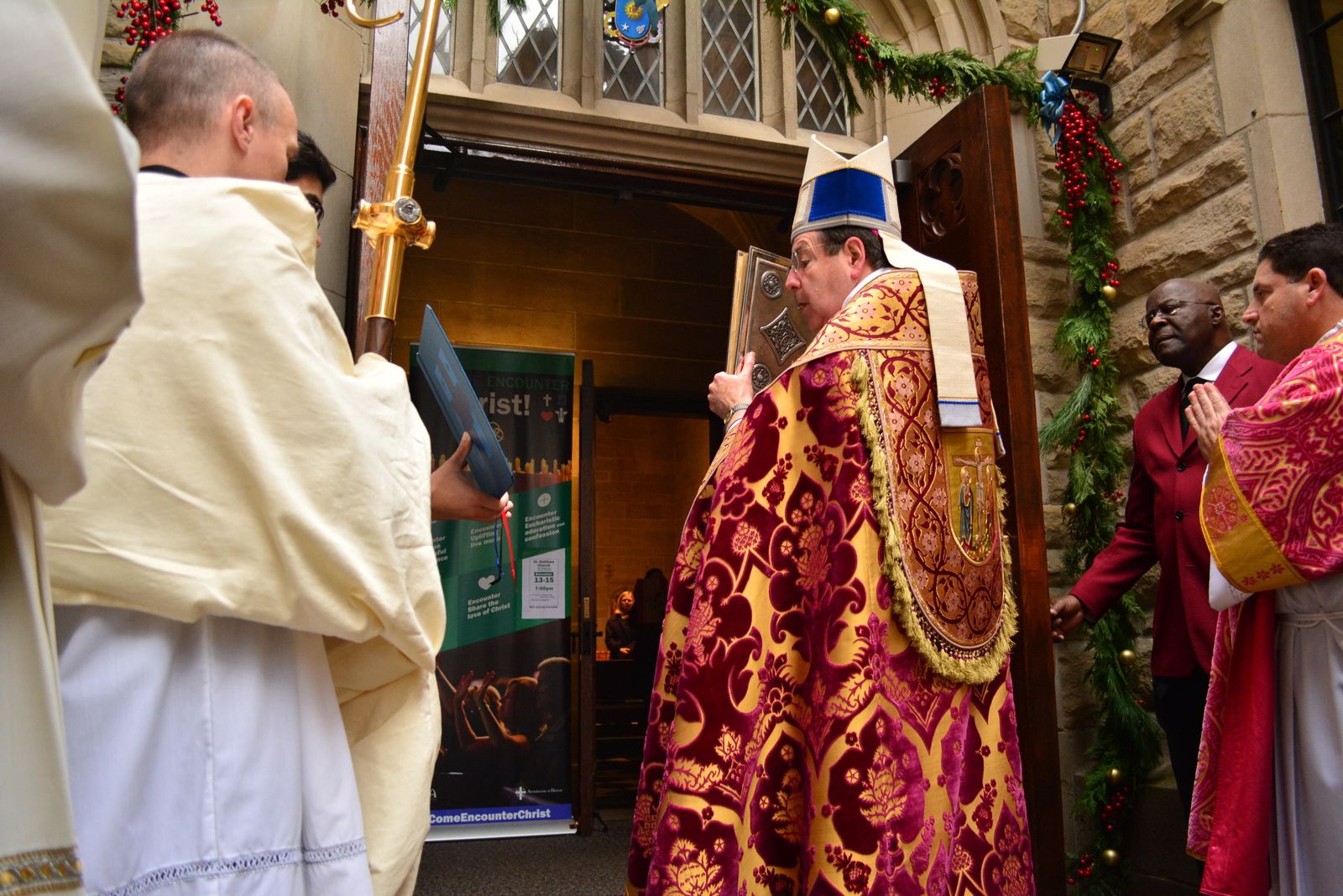 Archbishop Allen H. Vigneron holds the Book of the Gospels as he processes through the Holy Door at the Cathedral of the Most Blessed Sacrament on Dec. 13, 2015, at the beginning of the extraordinary Jubilee Year of Mercy in 2016. (Photo by Michael Stechschulte | Detroit Catholic)