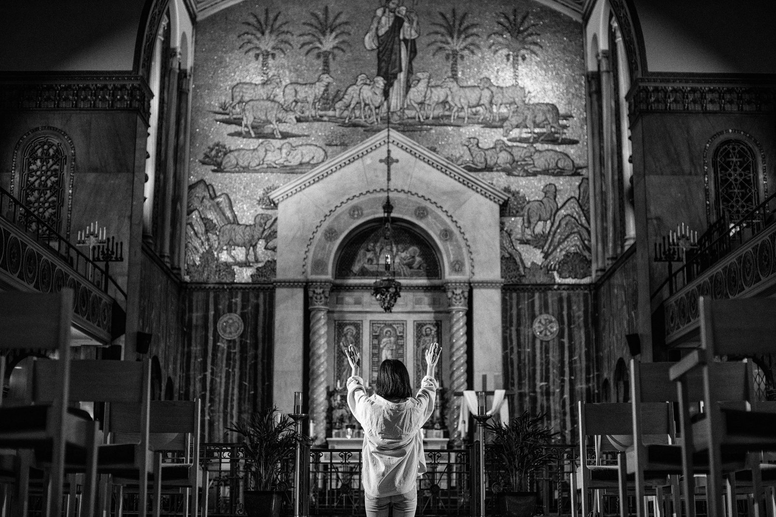Christine Kim of St. Aloysius Parish in downtown Detroit prays with arms extended before the Blessed Sacrament. Kim's story is one of those featured in the new I AM HERE campaign.