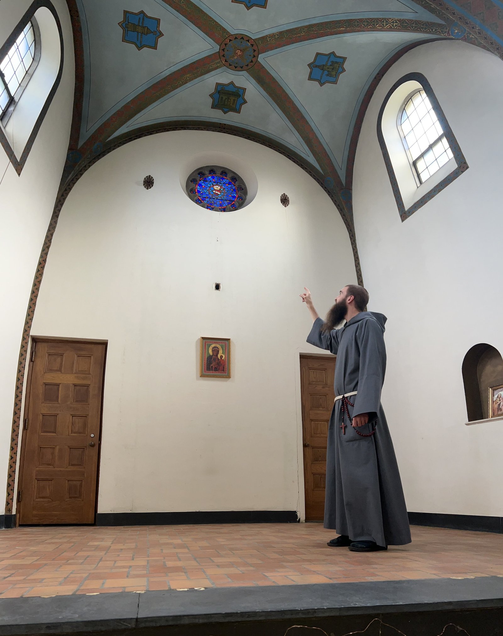 Un fraile señala una vidriera encima donde se colocará el altar dentro de la capilla, que actualmente se encuentra en remodelación. El nombre de la capilla tendrá un tema mariano, indicó el padre Fornwalt.