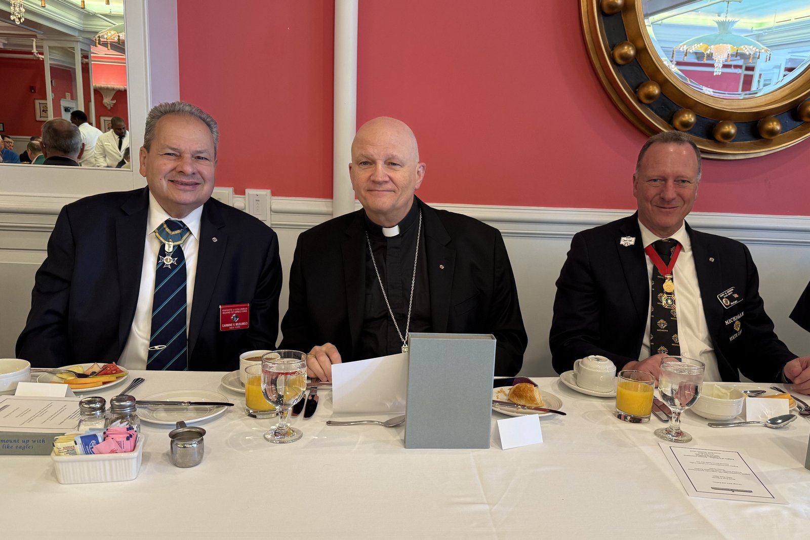 Archbishop Weisenburger sits between Carmine Musumeci, left, supreme director of the Knights of Columbus, and Barry Borsenik, right, state deputy of the Michigan Knights of Columbus.