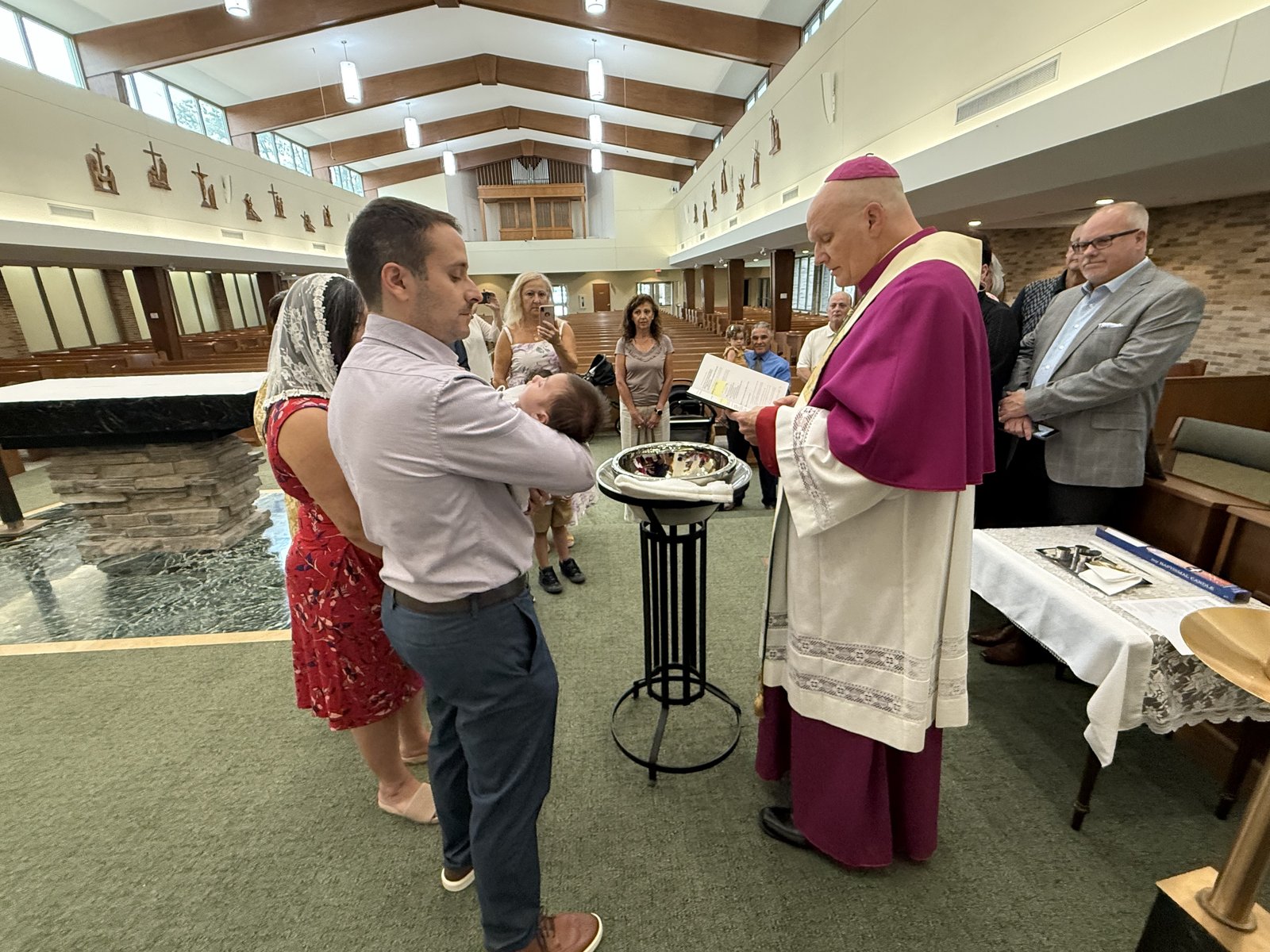 Archbishop Weisenburger baptizes Matteo Jude Nelson as his family looks on.