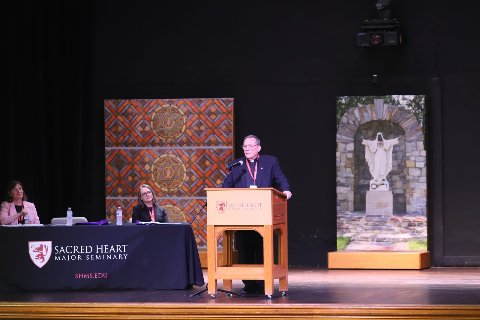 Fr. Peter Ryan, SJ, emcee for Sacred Heart Major Seminary's academic conference, "'What Is Man That You Are Mindful of Him?' Human Nature and Person Today," addresses attendees in the auditorium at the seminary.