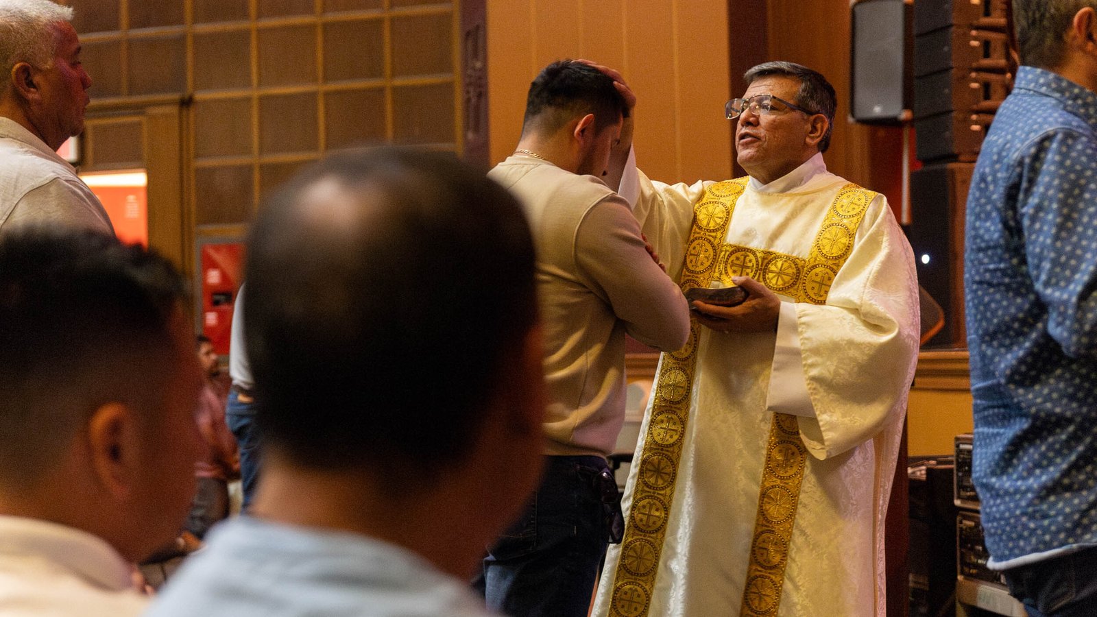 A man receives a blessing during Mass at the conference.