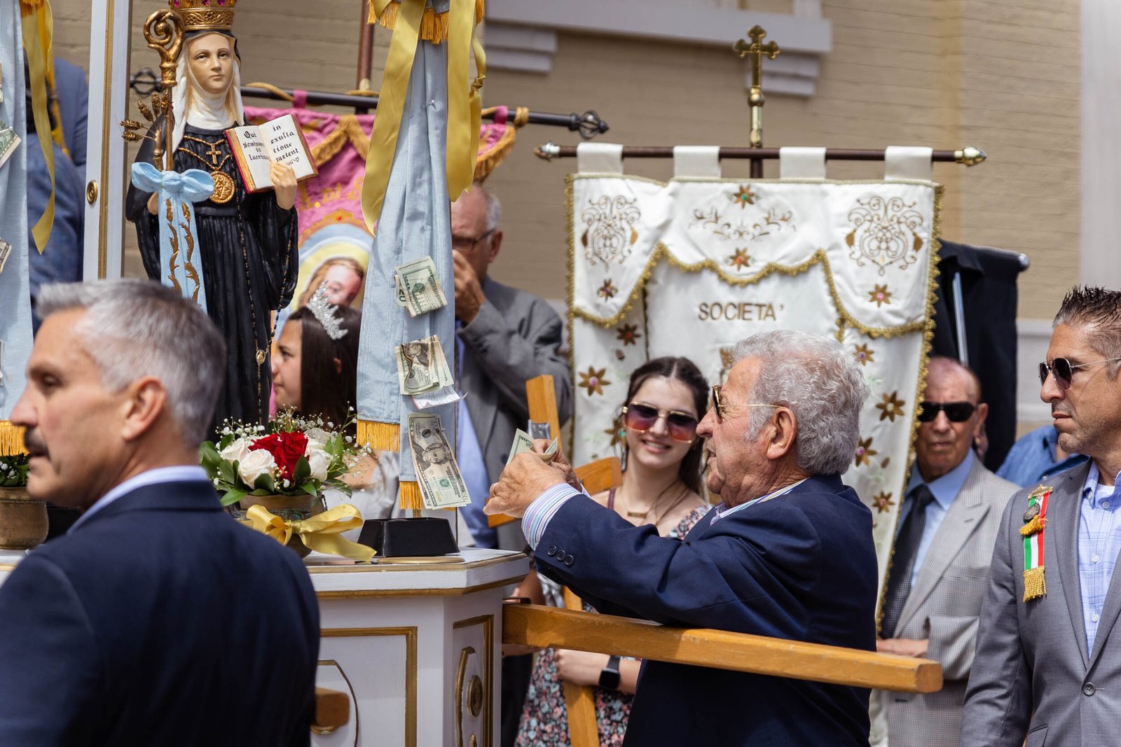 A member of the Santa Fara Club pins money to the statue of Santa Fara as an offering to the Church.