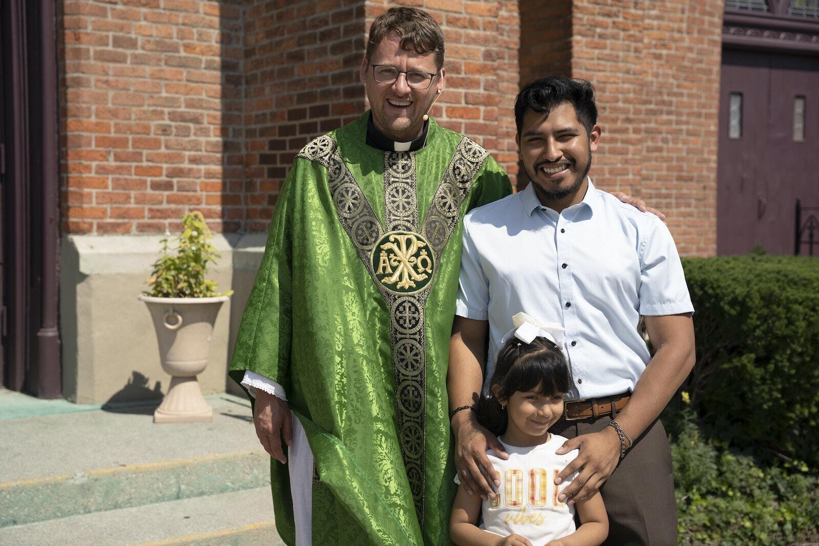 El P. Adams posa para una foto junto a los feligreses Arturo y Casey Medina de la Parroquia Most Holy Trinity. El P. Adams se despidió de sus feligreses luego de la misa, pero les aseguró que vendría de visita. (Gabriella Patti | Detroit Catholic)