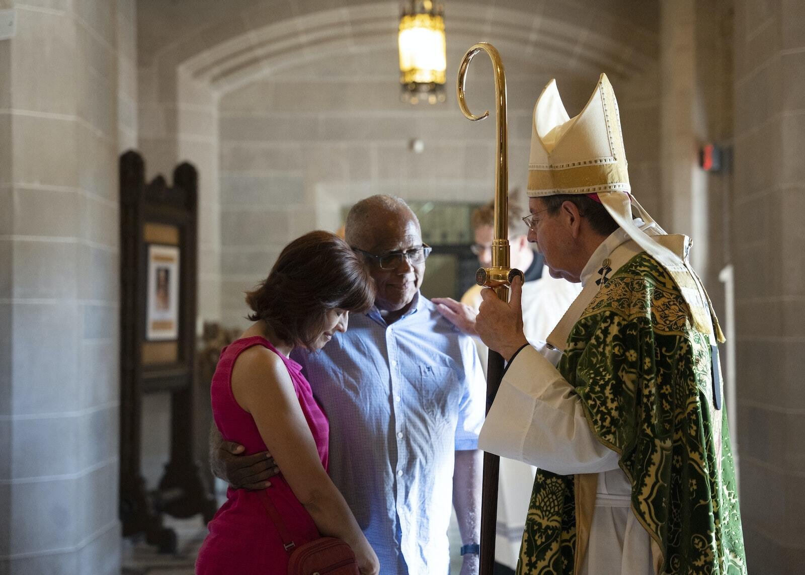 El Arzobispo Vigneron reza con una pareja después de la Misa en el vestíbulo de la Cathedral of the Most Blessed Sacrament.