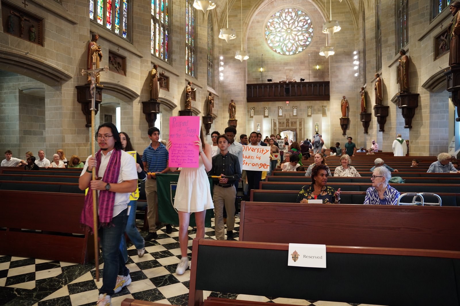 Students and members of Strangers No Longer carry banners and signs in procession before the start of Mass for the Jubilee of Migrants at the Cathedral of the Most Blessed Sacrament in Detroit.