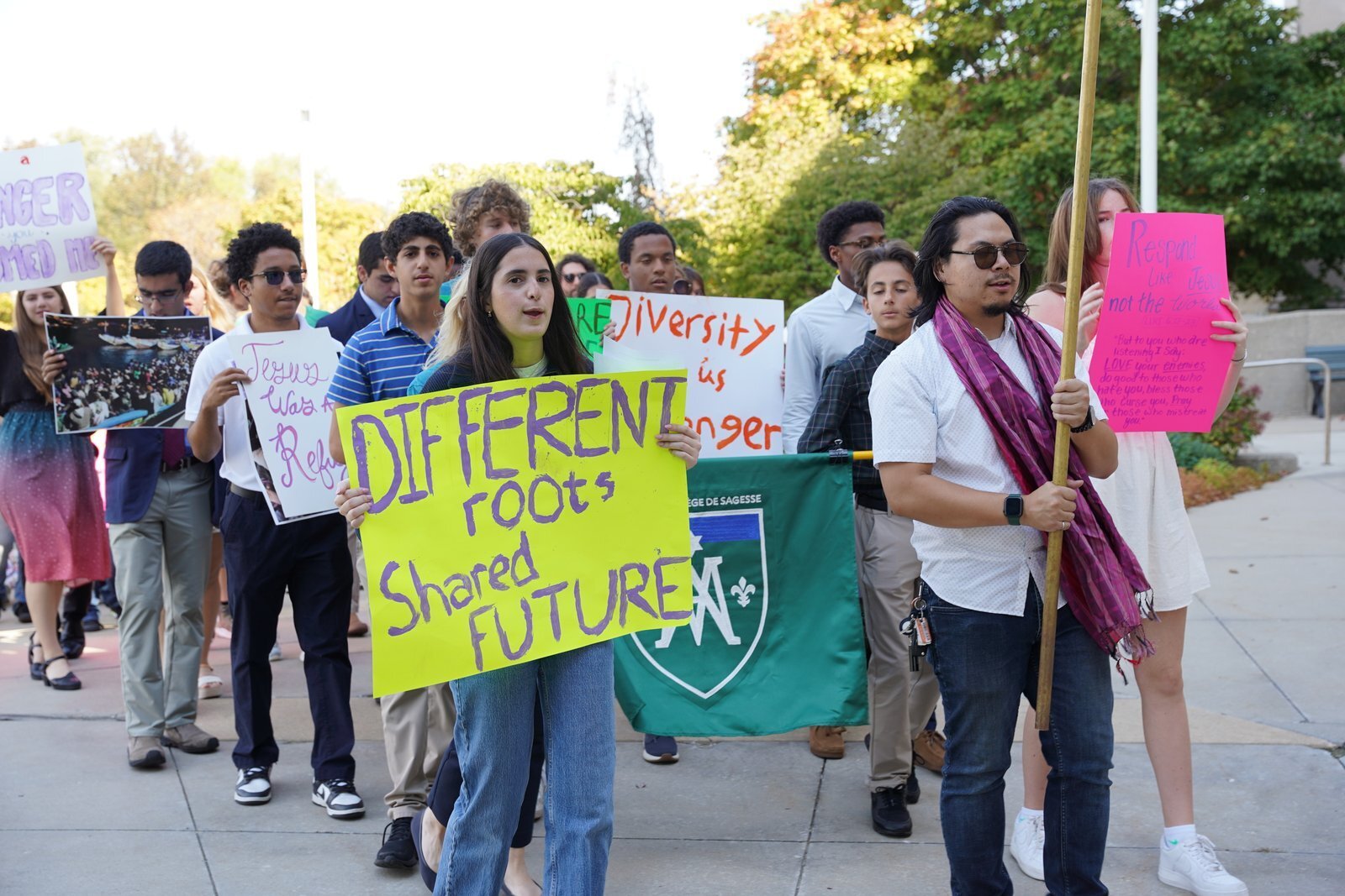 Integrantes de Strangers No Longer recorren el campus de la Cathedral of the Most Blessed Sacrament en Detroit antes de la Misa por la Jornada Mundial del Migrante y del Refugiado, celebrada en octubre, portando carteles en apoyo a los derechos de los inmigrantes. (Foto: Daniel Meloy | Detroit Catholic)