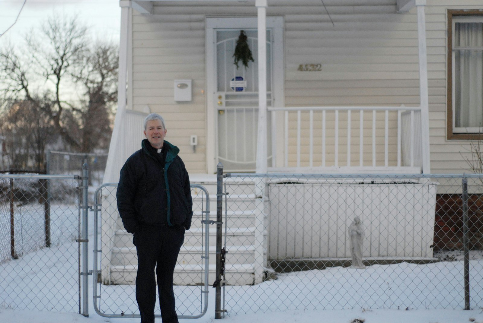 Mons. Trapp posa para una foto durante el 2016 frente a una casa que compró cerca de la St. Augustine and St. Monica Parish. Lo hizo con la ayuda de una organización sin fines de lucro que él mismo fundó para revitalizar el vecindario y arreglar casas para las personas de bajos recursos. (Michael Stechschulte | Detroit Catholic)
