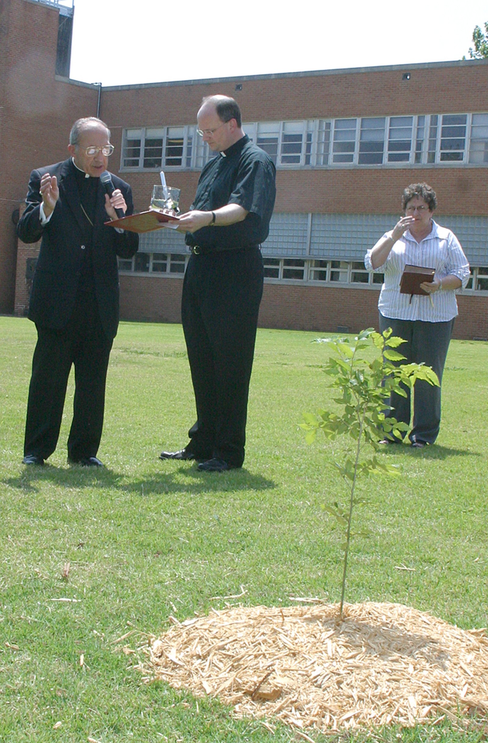 In this 2005 photo, then-Fr. Weisenburger assists Oklahoma City Archbishop Eusebius J. Beltran in blessing a newly planted tree to memorialize the victims of the 1995 bombing of the Murrah Federal Building. As a young priest, Archbishop Weisenburger served as an on-site chaplain to rescue workers in the aftermath of the tragedy. (Courtesy of the Sooner Catholic)