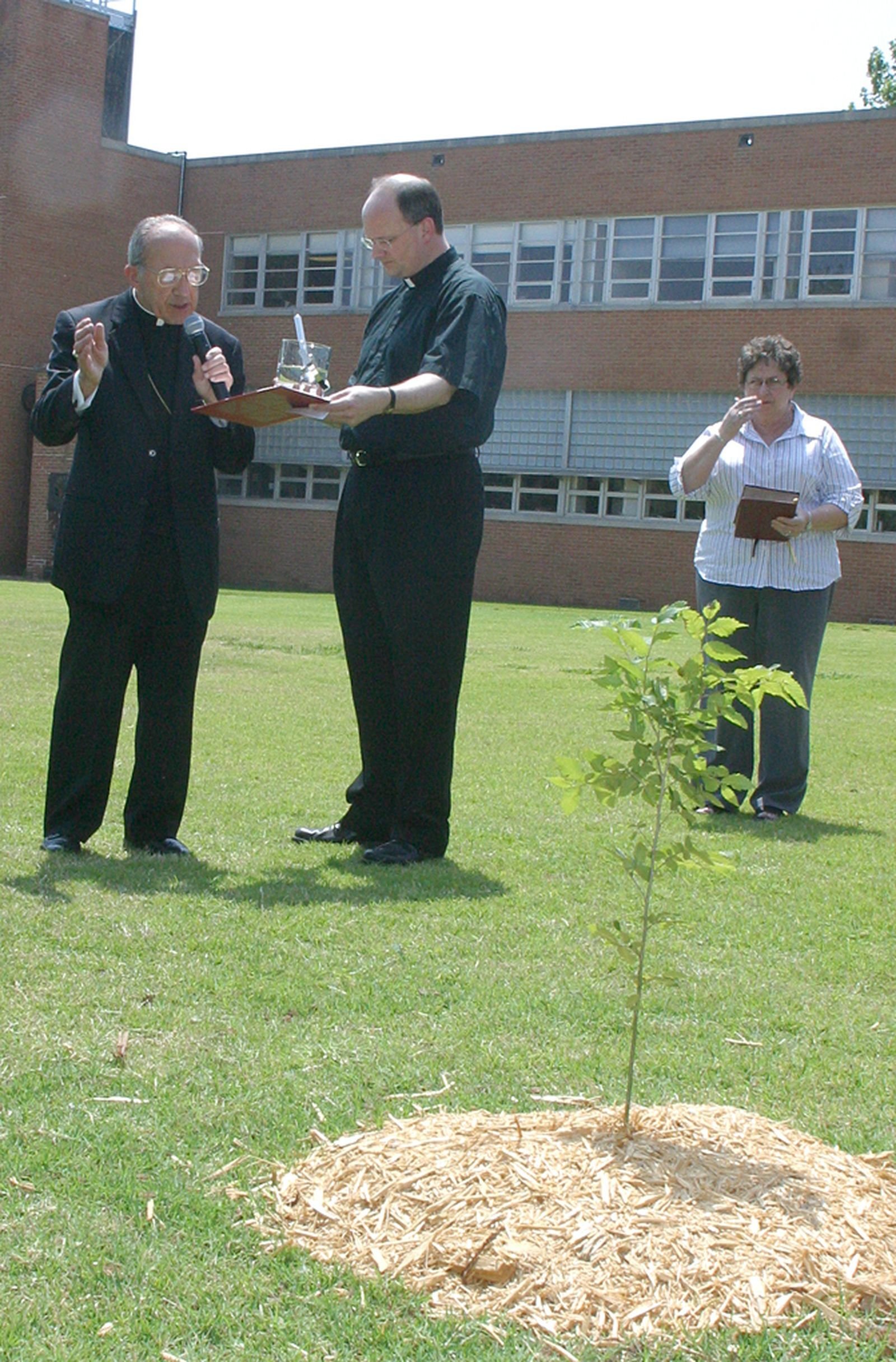 En esta foto de 2005, el entonces P. Weisenburger acompaña al Arzobispo de Oklahoma City, Eusebius J. Beltran, en la bendición de un árbol recién plantado en memoria de las víctimas del atentado de 1995 contra el edificio federal Murrah. Siendo un sacerdote joven, el Arzobispo Weisenburger sirvió como capellán en el lugar, brindando apoyo a los rescatistas en los días posteriores a la tragedia. (Foto cortesía de Sooner Catholic)