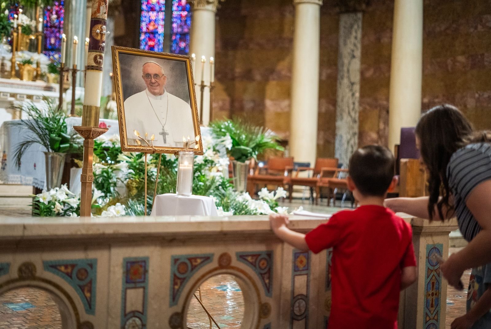 A young boy and a woman pause to pray for Pope Francis before an image of the late pontiff in the sanctuary at Most Holy Redeemer Parish in southwest Detroit.