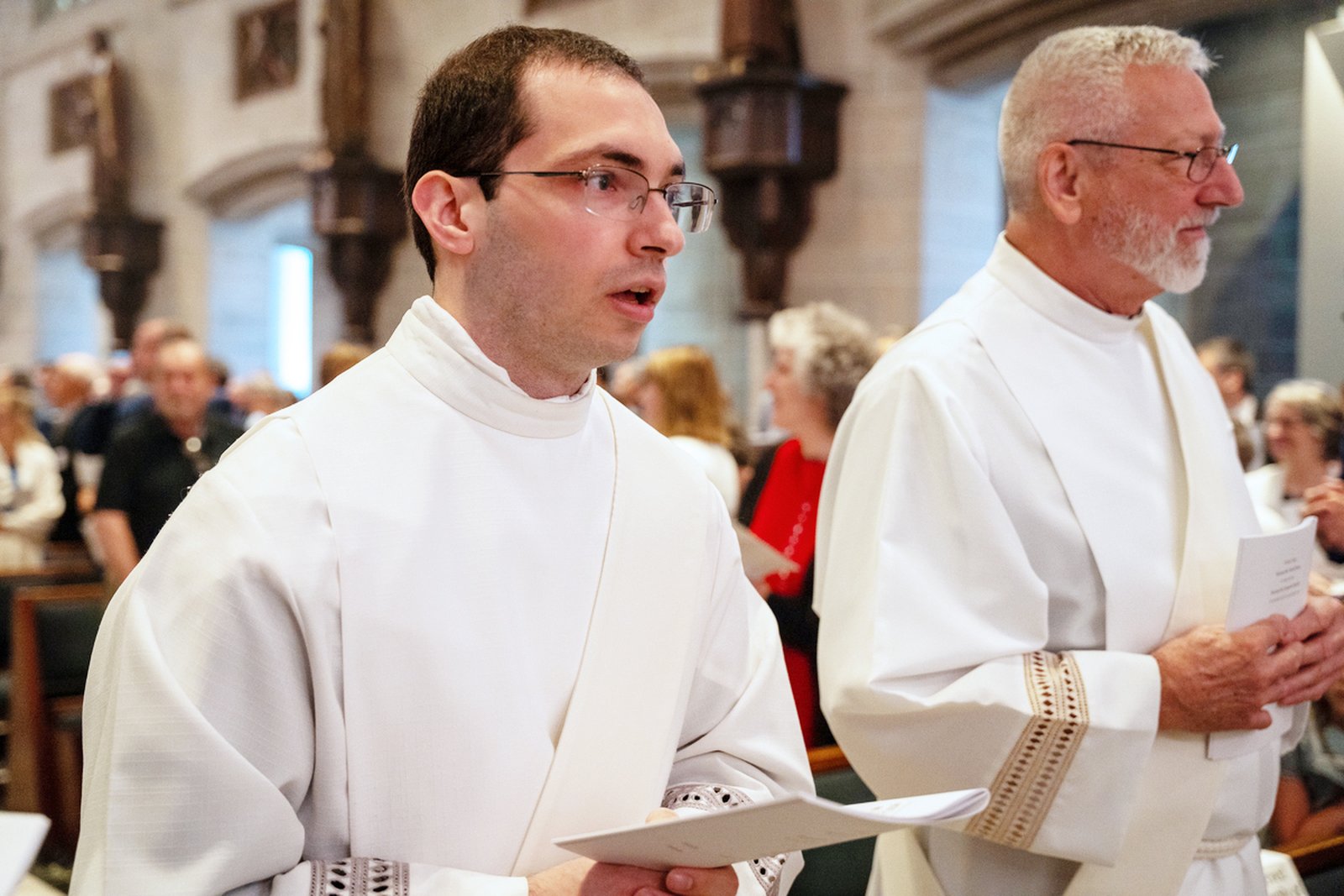 Then-Deacons Benjamin Schroder, left, and Pat Bruen enter the cathedral as friends and family look on during the start of their ordination Mass.