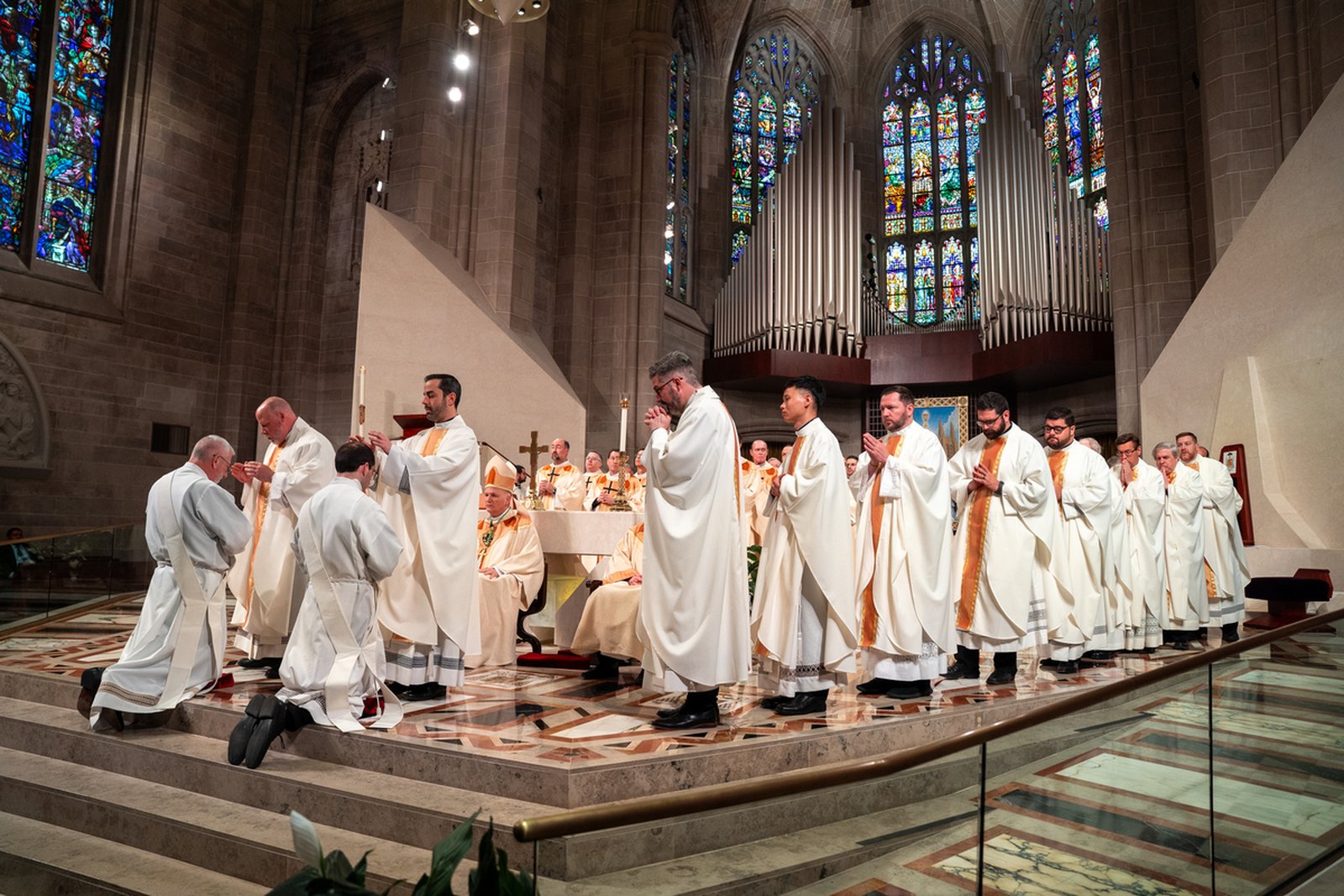 Priests of the Archdiocese of Detroit lay their hands on the heads of Fr. Bruen and Fr. Schroder, praying for them as they begin their vocation as ministers of God's word and sacrament.