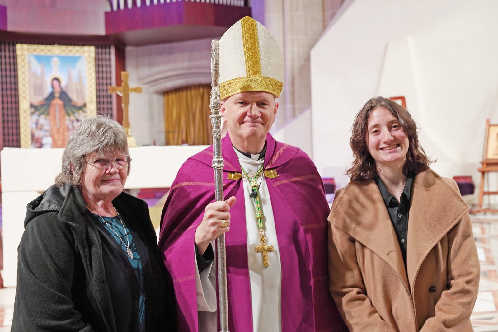 Alex Schultz, 22, will enter the Church this Easter vigil at St. John Fisher Chapel University Parish in Auburn Hills. Schultz, right, is pictured with Archbishop Weisenburger and her confirmation sponsor, Leslie Kowalski, after the Rite of Election liturgy on Feb. 22.