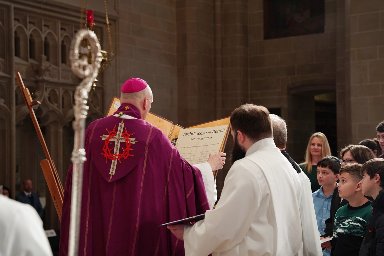 El arzobispo Weisenburger revisa los nombres de los catecúmenos que serán recibidos en la Iglesia esta Vigilia Pascual, inscritos en el Libro de los Elegidos. Durante la celebración, recordó a los catecúmenos y candidatos que fue el Padre quien los eligió para seguir a Cristo y a su Iglesia.