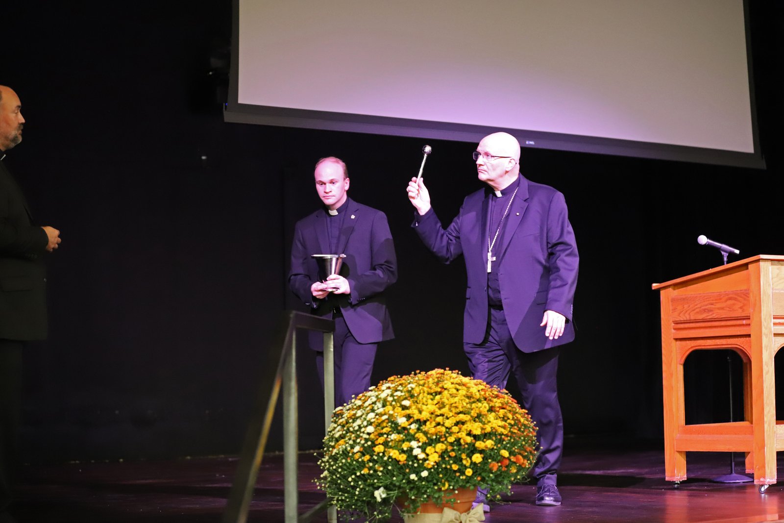 Archbishop Edward J. Weisenburger sprinkles holy water on the newly renovated stage during a blessing Sept. 20 of Sacred Heart Major Seminary's century-old auditorium.