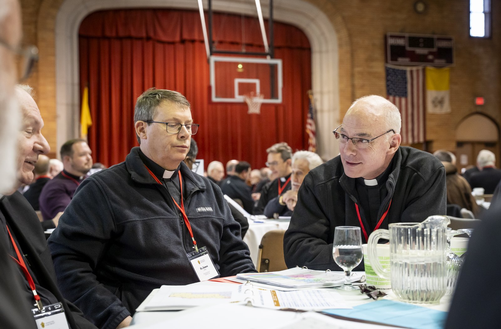 Fr. Jim Kean, left, and Fr. J.J. Mech, right talk with fellow priests March 3 at Sacred Heart Major Seminary during a review workshop to discuss proposed pastorate models.