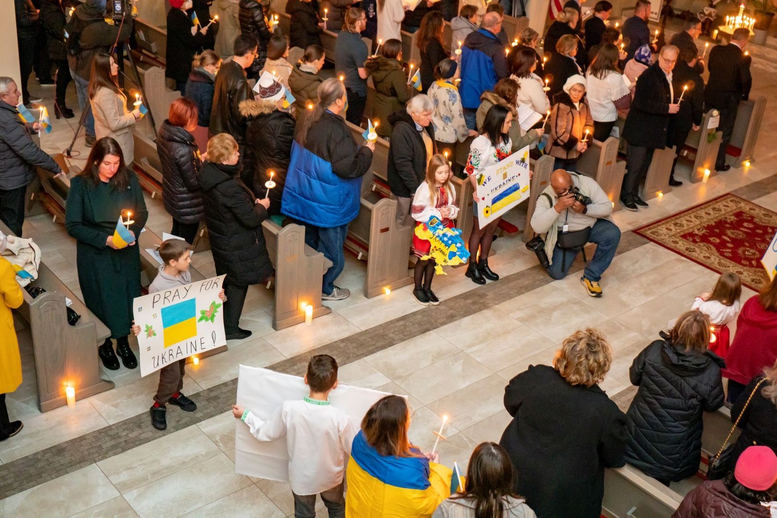 Children hold signs of support for Ukraine as parishioners hold candles during a prayer vigil Feb. 24 at St. Mary the Protectress Ukrainian Orthodox Cathedral in Southfield. (Matthew Rich | Special to Detroit Catholic)