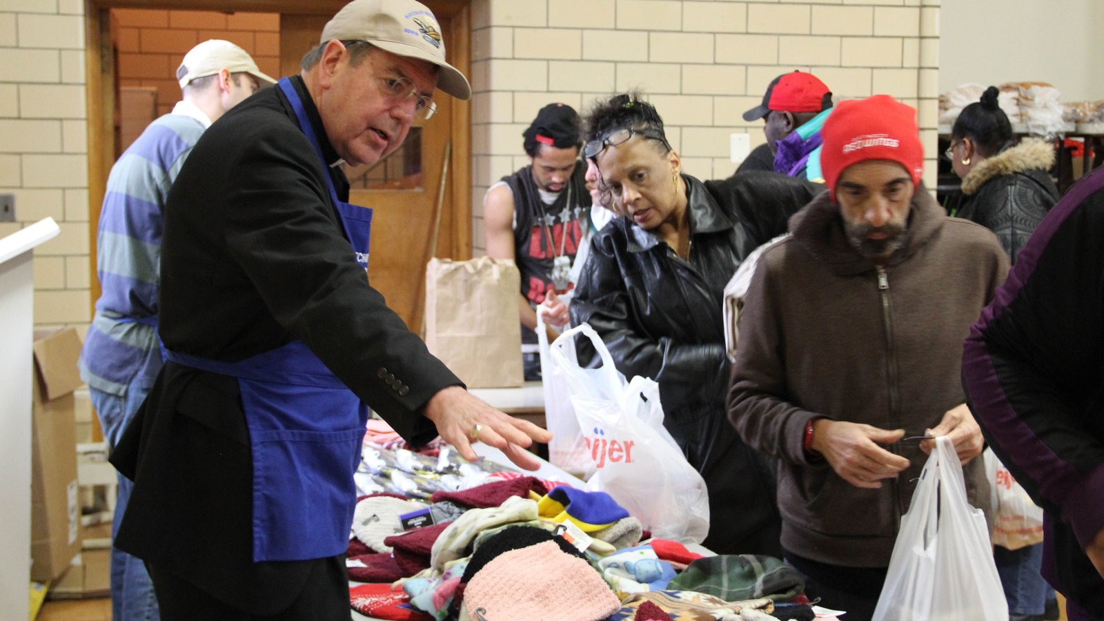 Archbishop Vigneron helps hand out hats, gloves and scarves at the Matchan Nutrition Center in Pontiac on Dec. 22, 2016. The soup kitchen, which serves hot meals to approximately 500 people every Tuesday and Thursday, is in the gym of St. Vincent de Paul Church, part of St. Damien of Molokai Parish. (Jonathan Francis | Detroit Catholic file photo)