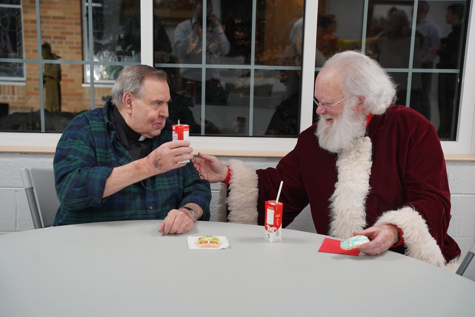 Fr. Terry Kerner, pastor of St. Kateri Parish, shares some milk and cookies with Santa Claus following during a surprise visit to St. Kateri on Jan. 22.