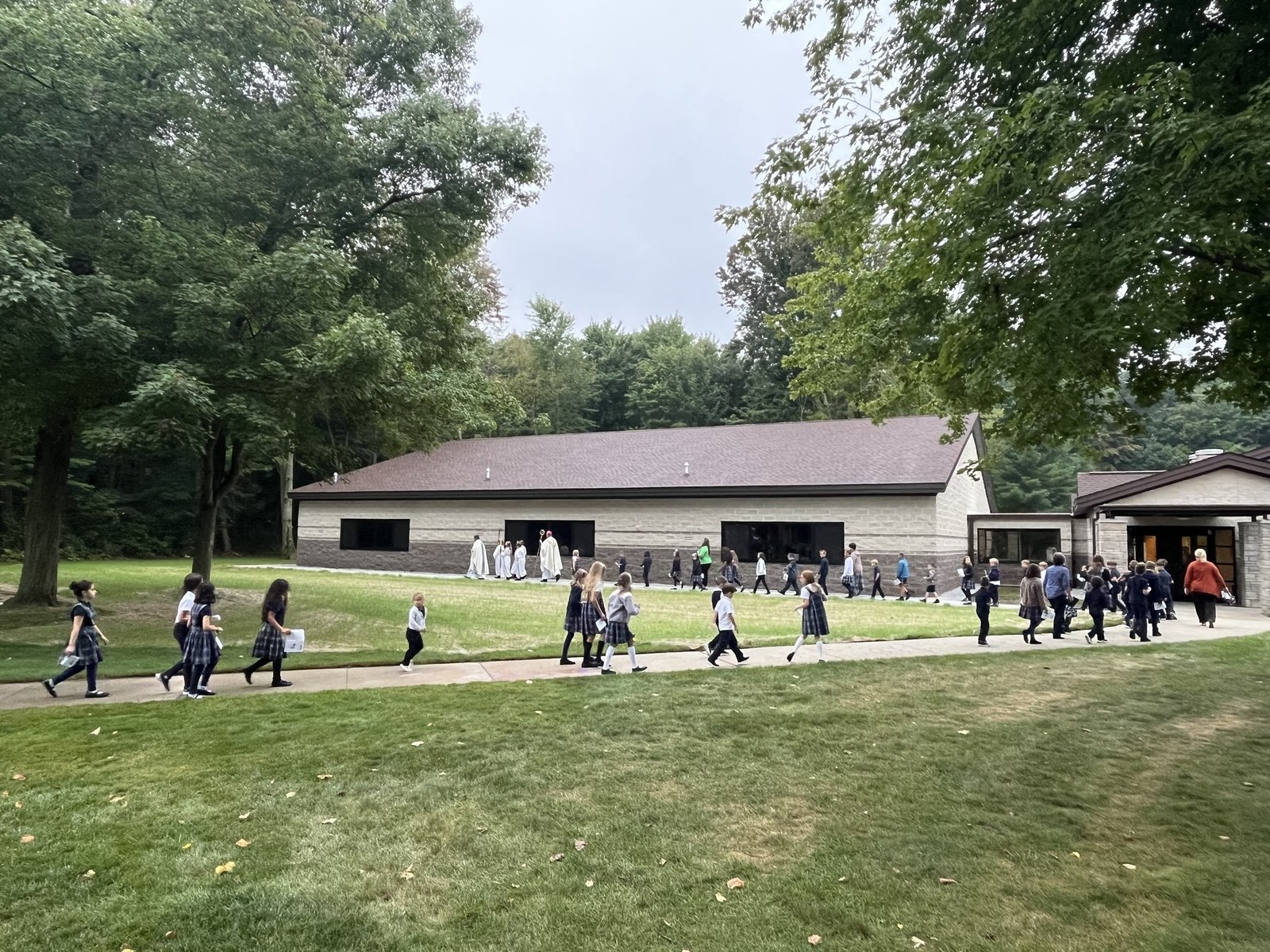 Students walk from the parish, where Bishop Fisher celebrated Mass, to the new school addition on Sept. 6.