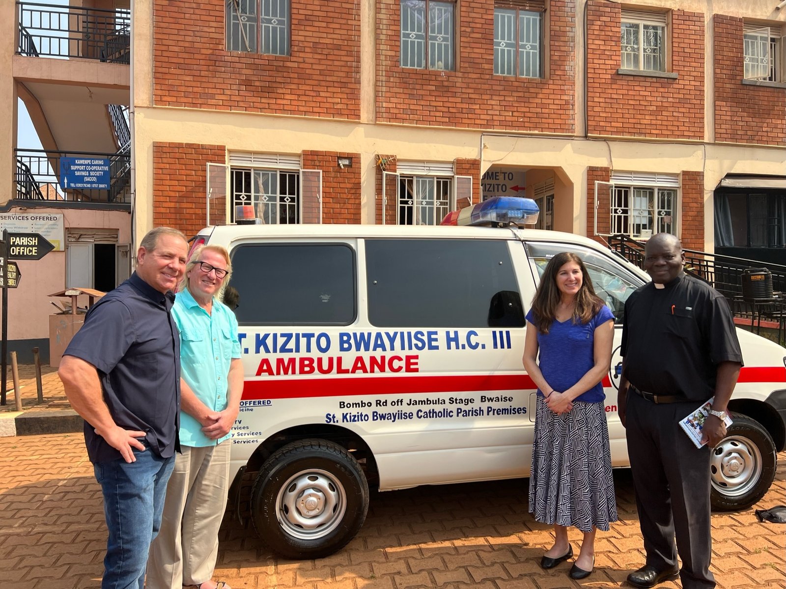 Chuck Salter, Bill Tulloch, Jasmin Walker and Msgr. John Ssebayigga are pictured in front of the 24/7 medical clinic and ambulance built and purchased by Our Lady of Good Counsel parishioners.