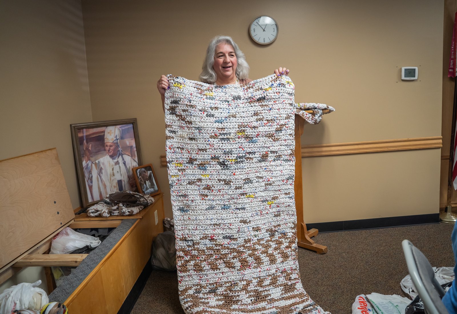 Nancy Trela holds up a crocheted mat made of "plarn," or plastic yarn. While most of the women work on the pad project, some crochet mats, totes and sleeping bags that are donated to local organizations that help the unhoused.