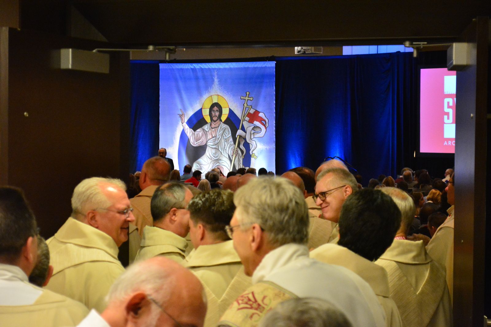 An image of the risen Christ is seen inside the synod hall as clergy, laity and religious file into the room during the opening session of Synod 16 on Nov. 18, 2016. (Michael Stechschulte | Detroit Catholic)