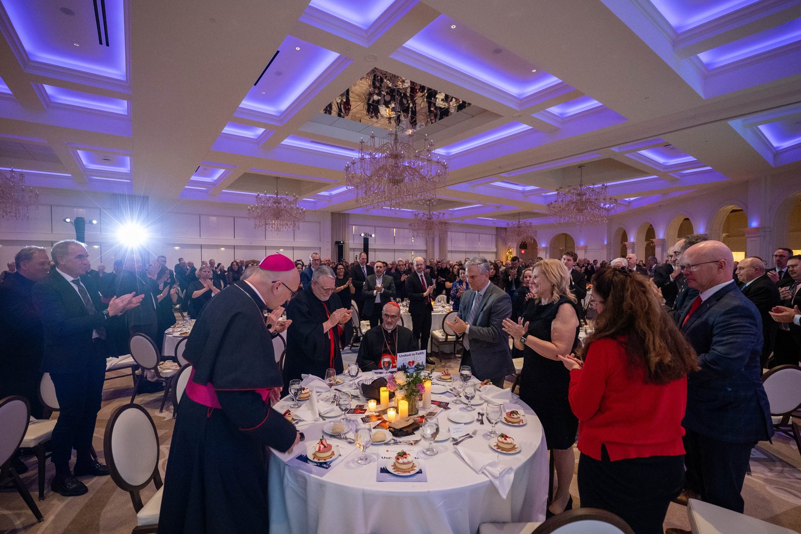 Archbishop Weisenburger leads a round of applause for Cardinal Pizzaballa during the conclusion of a Dec. 5 fundraising event at St. John's Resort.