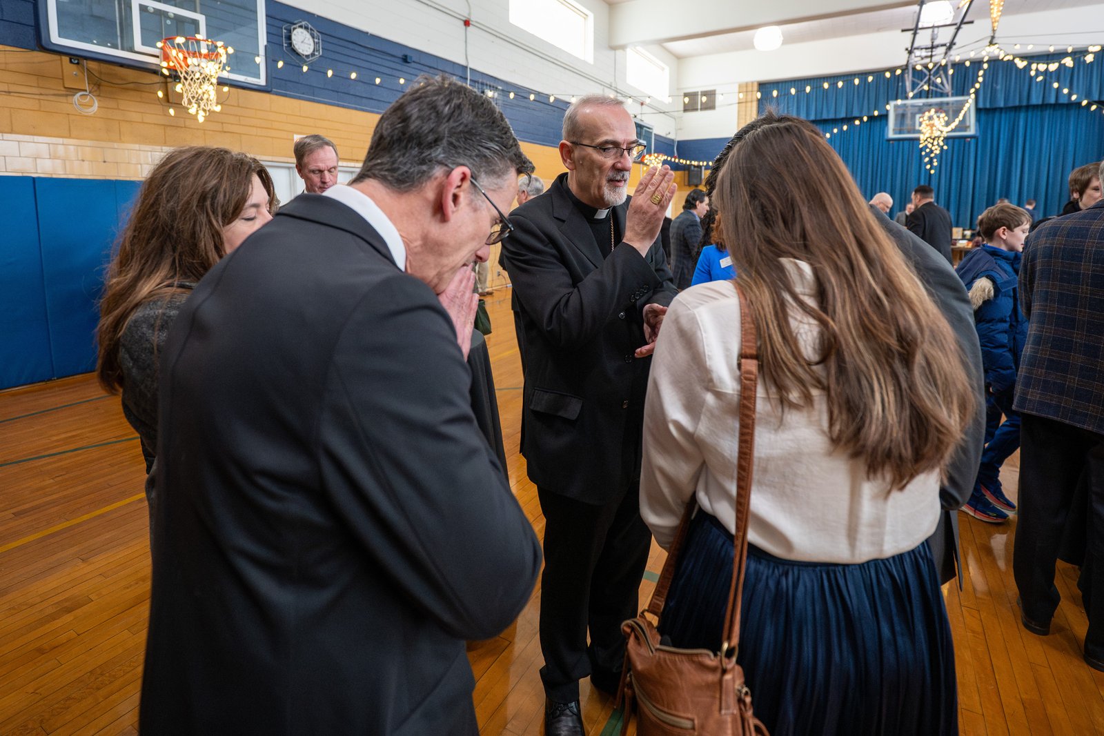 Cardinal Pizzaballa blesses families during a brief lunch reception following Mass in the Shrine Grade School gymnasium.
