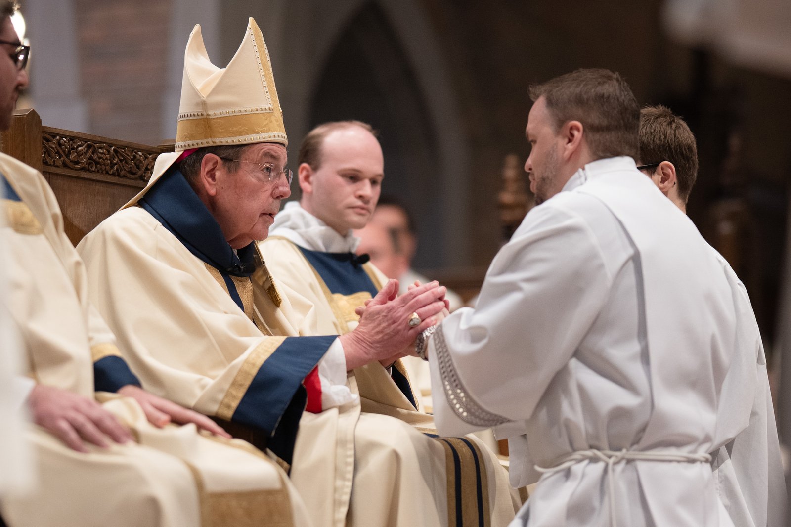 Archbishop Vigneron clasps the hands of Deacon Anthony Riley, who will serve the Church as a transitional deacon during his final year of seminary formation, during the ordination rite.