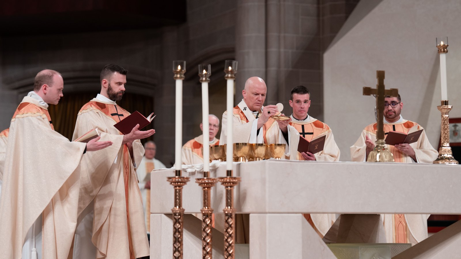 Los nuevos sacerdotes de Detroit celebran la Eucaristía por primera vez, orando sobre las ofrendas de pan y vino mientras el arzobispo Weisenburger eleva la hostia.