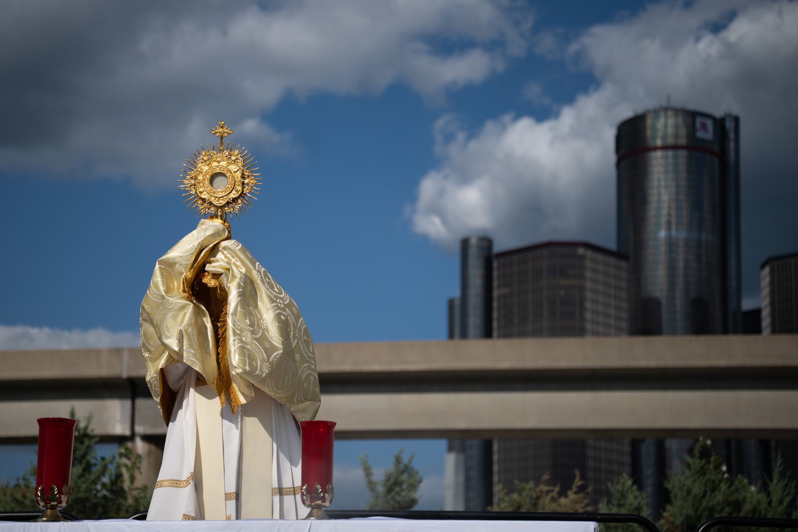 El arzobispo de Detroit, Mons. Edward J. Weisenburger, bendice a la ciudad de Detroit con el Renaissance Center en el fondo el 22 de julio, mientras eleva la custodia con el Santísimo Sacramento al concluir el Reavivamiento «Rising from the Ashes», un evento eucarístico que atrajo a 5.200 católicos al corazón de la ciudad. (Foto de Tim Fuller | Especial para Detroit Catholic)