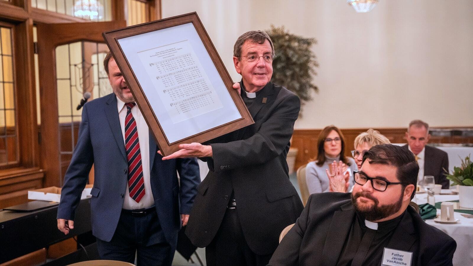 El Arzobispo Vigneron sostiene una copia enmarcada de un himno escrito en su honor que le regalaron el 16 de octubre de 2023, durante la celebración de su 75 cumpleaños. (Valaurian Waller | Detroit Catholic)