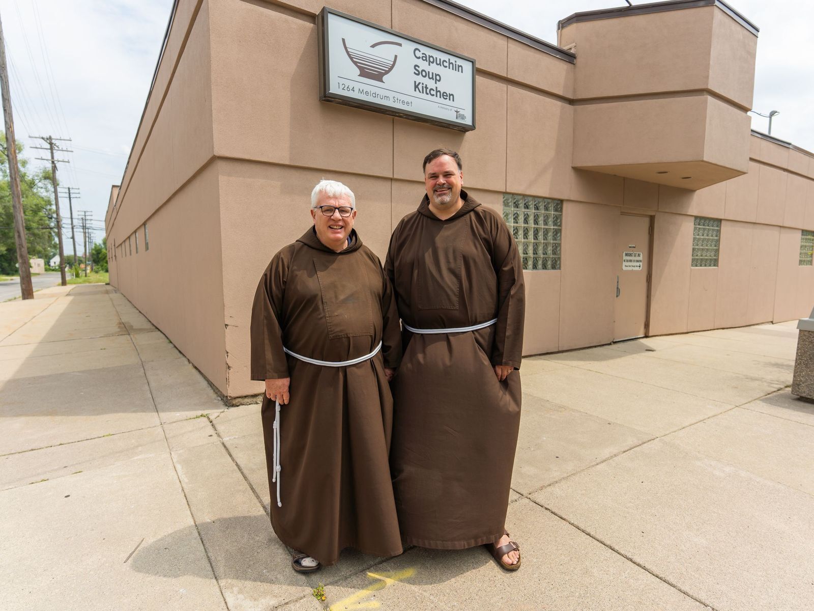 El Hno. Gary Wegner, OFM Cap., izquierda, director ejecutivo de la Capuchin Soup Kitchen, se encuentra junto al Hno. Steven Kropp, OFM Cap., director del Solanus Casey Center, frente a la Capuchin Soup Kitchen en agosto de 2021. (Foto Valaurian Waller | Detroit Catholic)